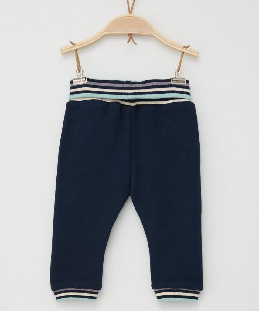 Details:  These navy blue baby jogg pants are both stylish and comfortable. Featuring an elastic waistband and leg cuffs with contrasting stripes, these pants are perfect for your active little one. The stretchy material allows for free movement and the stylish design adds a pop of color to any outfit.  Color: Navy blue  Composition:  095%CO 005%EL  
