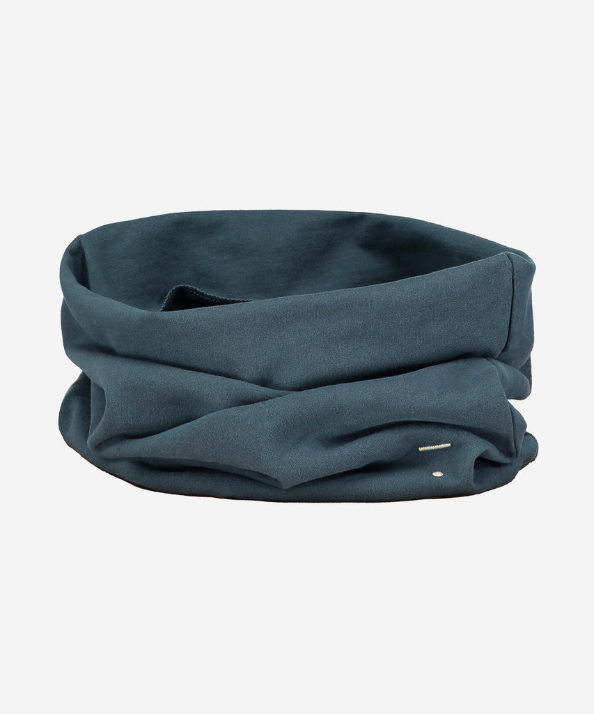Details: A cowl scarf made from soft organic cotton fleece and has baby lock stitched edges. Logo is stitched on the bottom right side of the scarf.  Color: Blue Grey  Composition: 100% organic cotton fleece  Made in Portugal