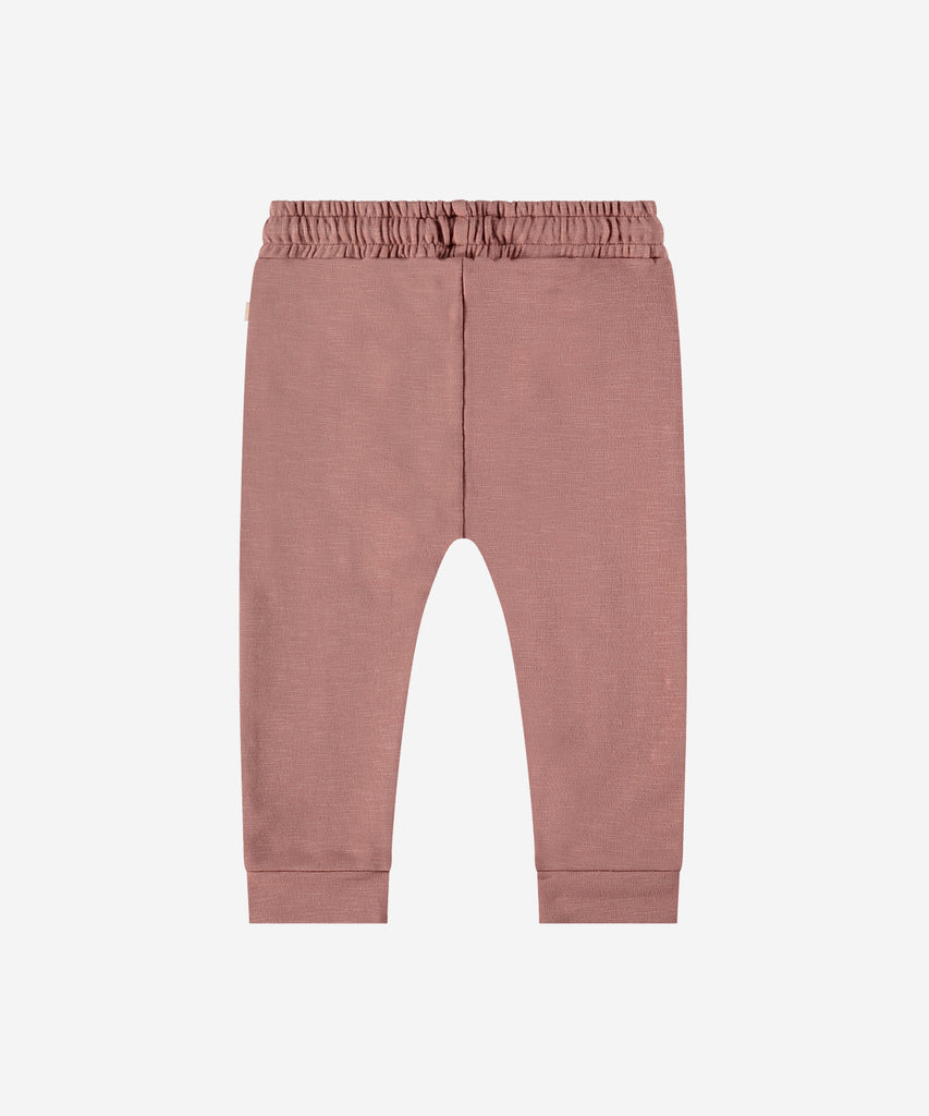 Details:  Introducing the soft Jogg Pants, designed for your little one's comfort. Crafted from a soft and durable fabric, these pants feature an elastic waistband for a secure and comfortable fit.  Ensure your child's adventures are as comfortable as can be with these Jogging Pants.  Color: Blossom  Composition: 95% BCI cotton/5% elasthan  