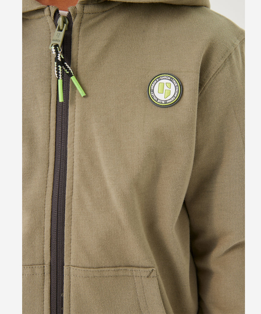Details:   Stay stylish in our Hooded Cardigan, featuring a zip closure and pockets for convenience. The ribbed arm cuffs and waistband ensure a comfortable fit. Available in a beautiful green summer color. Perfect for any casual day out.  Color: Green summer  Composition:  100% Cotton 