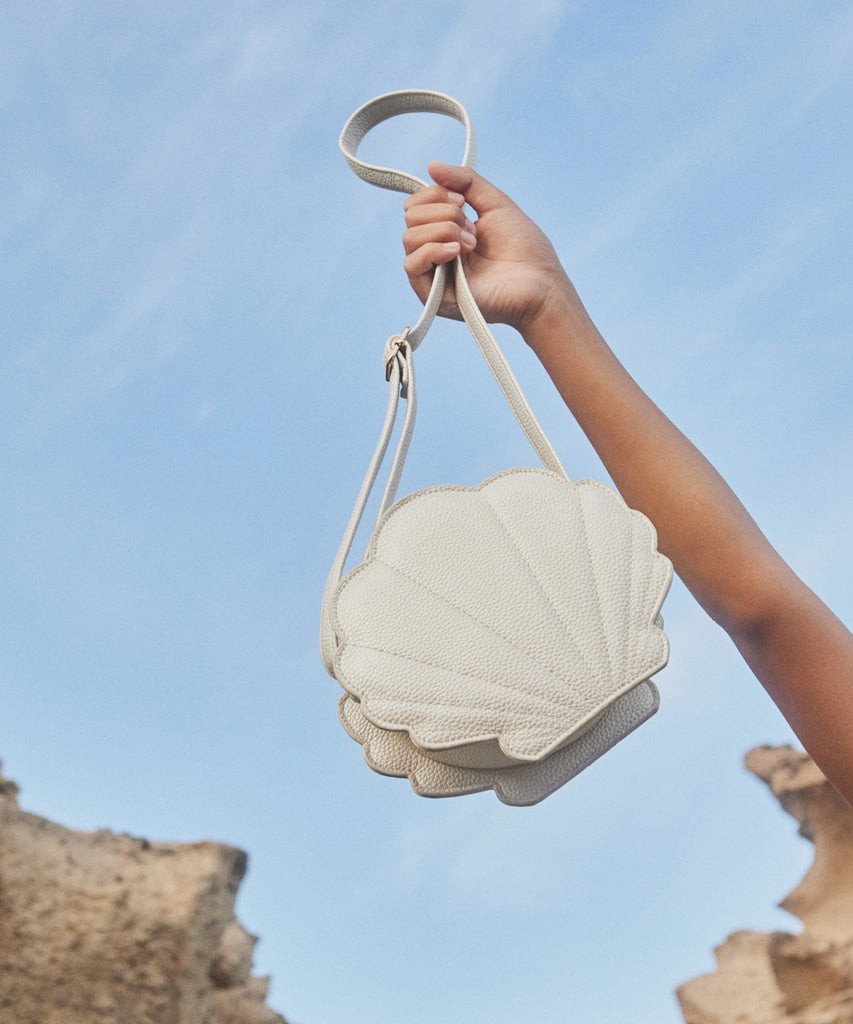 Details:  Our Seashell Cross Body bag is the perfect companion for any adventure! This bag features an adorable seashell design and zip closure to make sure your items are safe and secure. With this stylish bag, you're sure to be a hit no matter where your day takes you!  Color: Mother of pearl  Composition:  100% Polyurethane 