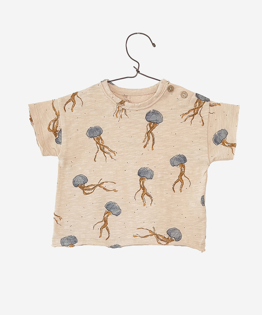 Details: This T-shirt is made of jersey stitch organic cotton, Crochet colour. It has short sleeves, a round neck, an opening on the shoulder with coconut buttons and our jellyfish print. Colour: Crochet  Composition:  100.0% Organic Cotton  