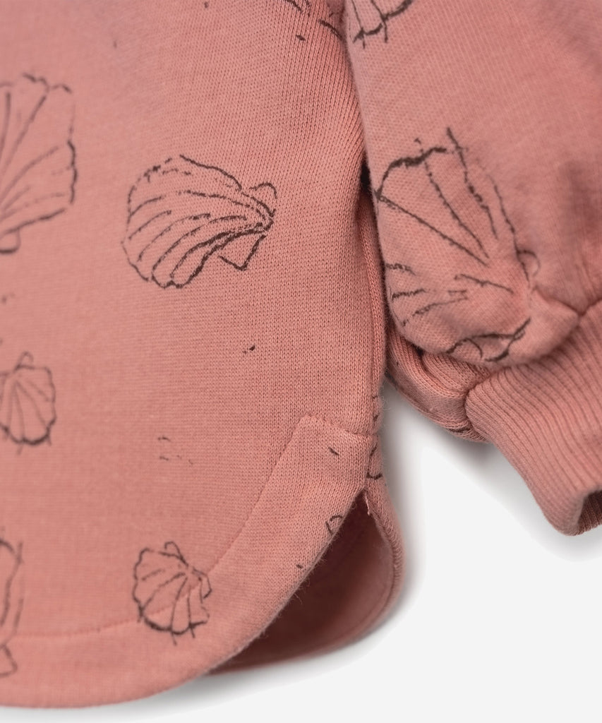Details:  This sweater is made of jersey stitch organic cotton, Coral colour. It has a rounded cut, a shoulder opening with coconut buttons, balloon sleeves, elasticated cuffs and our shells print.  Colour: Coral   Composition:  98.0% Organic Cotton,2.0% Elastane  