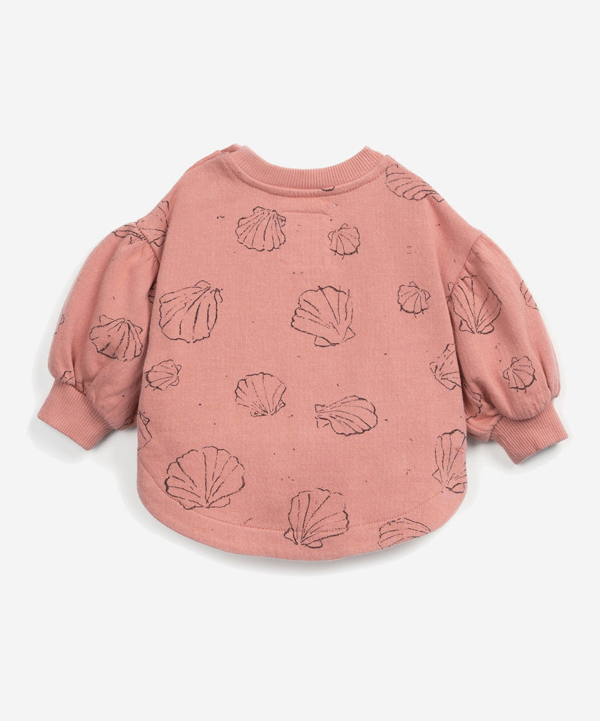 Details:  This sweater is made of jersey stitch organic cotton, Coral colour. It has a rounded cut, a shoulder opening with coconut buttons, balloon sleeves, elasticated cuffs and our shells print.  Colour: Coral   Composition:  98.0% Organic Cotton,2.0% Elastane  