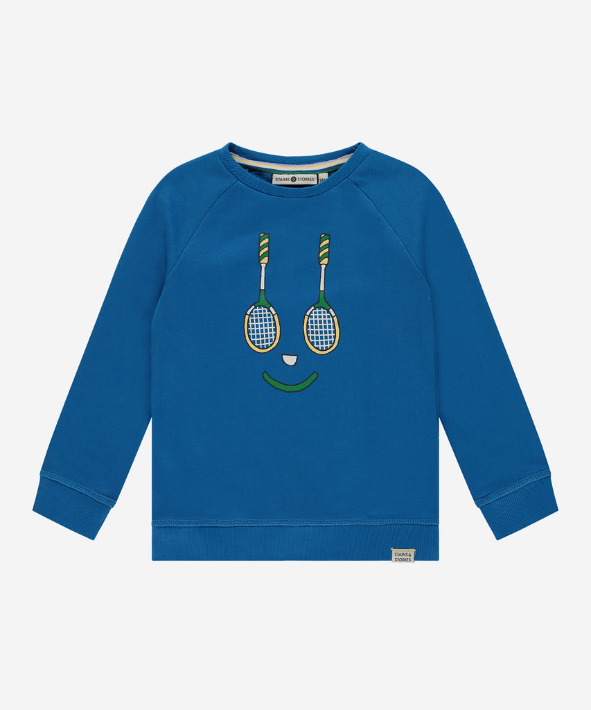 Details: Stay comfortable and stylish on the court with our Sweatshirt Tennis Smile River. Made with a round neckline, ribbed arm cuffs and waistband, and a vibrant blue color, this sweatshirt will keep you warm and fashionable while you play. The tennis smile print on the front adds a playful touch to your athletic look. Up to size 92, easy opening with 2 push buttons on the side of the collar.   Color: River blue  Composition: 100% BCI cotton  