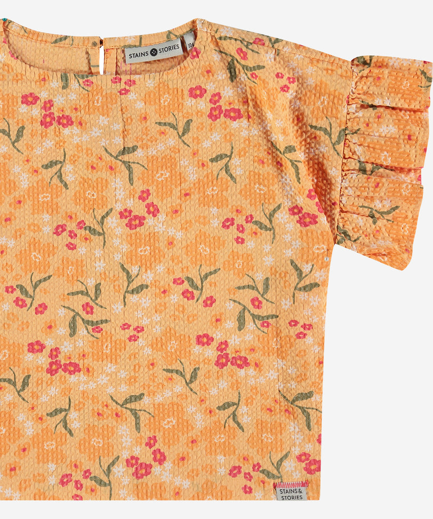 <strong>Details</strong>: Expertly crafted, this woven T-shirt features an all-over print of delicate flowers that adds a touch of whimsy to any outfit. The button closure at the back ensures a secure fit, while the short sleeves provide comfort and versatility. Elevate your wardrobe with this stylish and unique piece.&nbsp;<br><strong>Color</strong>: Cantaloupe&nbsp;<br><strong>Composition</strong>: Summer 24 &nbsp;