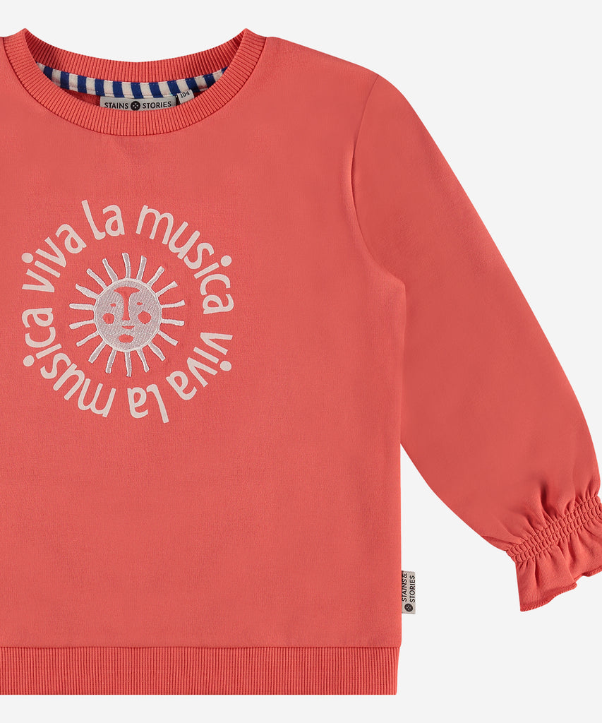 Details: This high-quality grapefruit-colored sweatshirt features an intricately embroidered sun and the phrase "viva la musica" on the front. Complete with a comfortable round neckline, this sweatshirt is perfect for music lovers looking to make a statement. Add a pop of color to your wardrobe with this stylish and unique sweatshirt. Up to size 92, easy opening with 2 push buttons on the side of the collar.  Color: Grapefruit  Composition: 95% BCI cotton/ 5% elasthane  