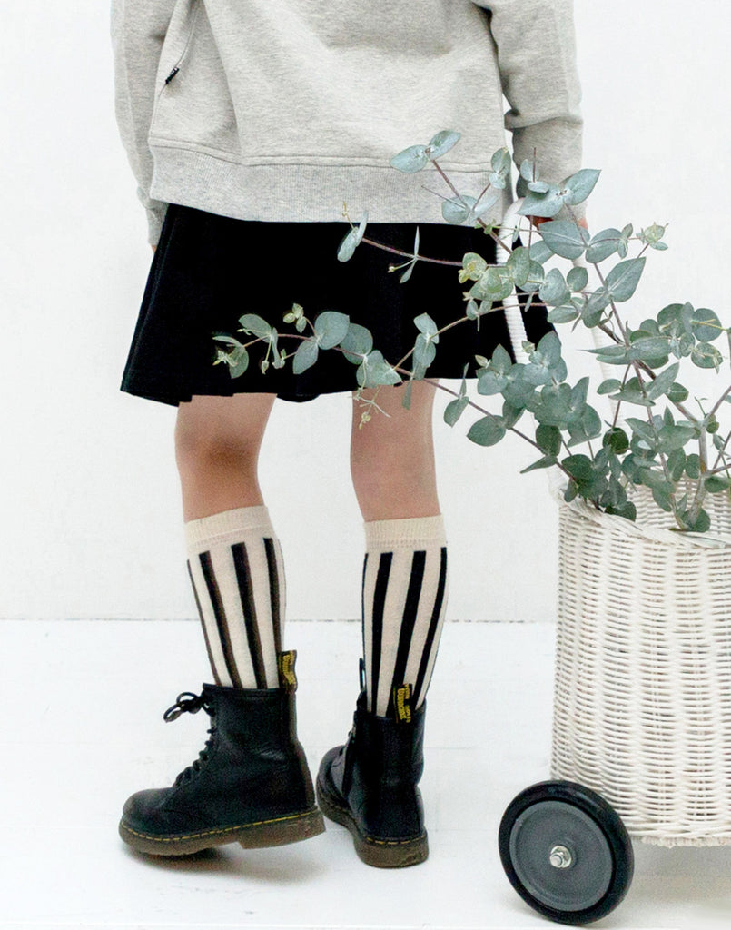 House of Jamie   Soft knitted knee socks with black- and cream colored vertical stripes. House of Jamie logo is knitted in the pattern on the bottom of the socks.  Color: Black, off white stripes.  Composition: 75% organic cotton 23% polyamide 2% elastane. 
