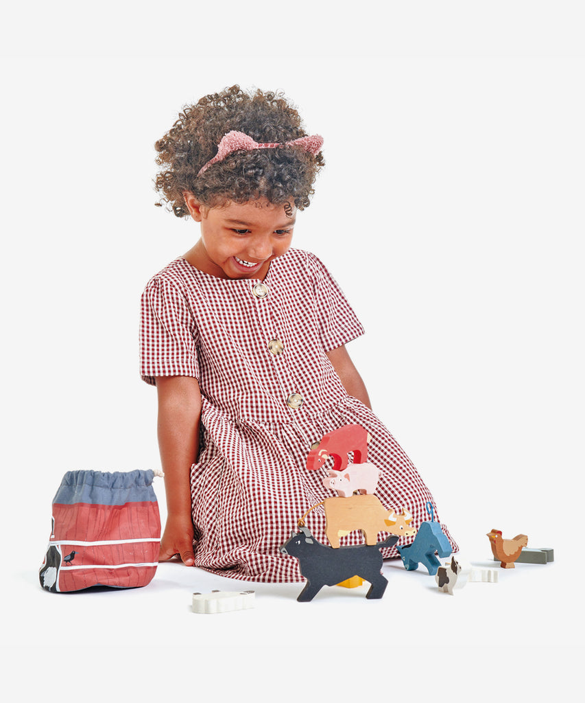 Tender Leaf®  How many animals can you stack?   Includes: 10 popular farmyard animals, a wheelbarrow, and a hay bale, all contained in a Barn style drawstring bag.  Age: 3 Years and older    Size: 13 x 13 x 13cm  Composition: sustainable and/or  recycled wood 